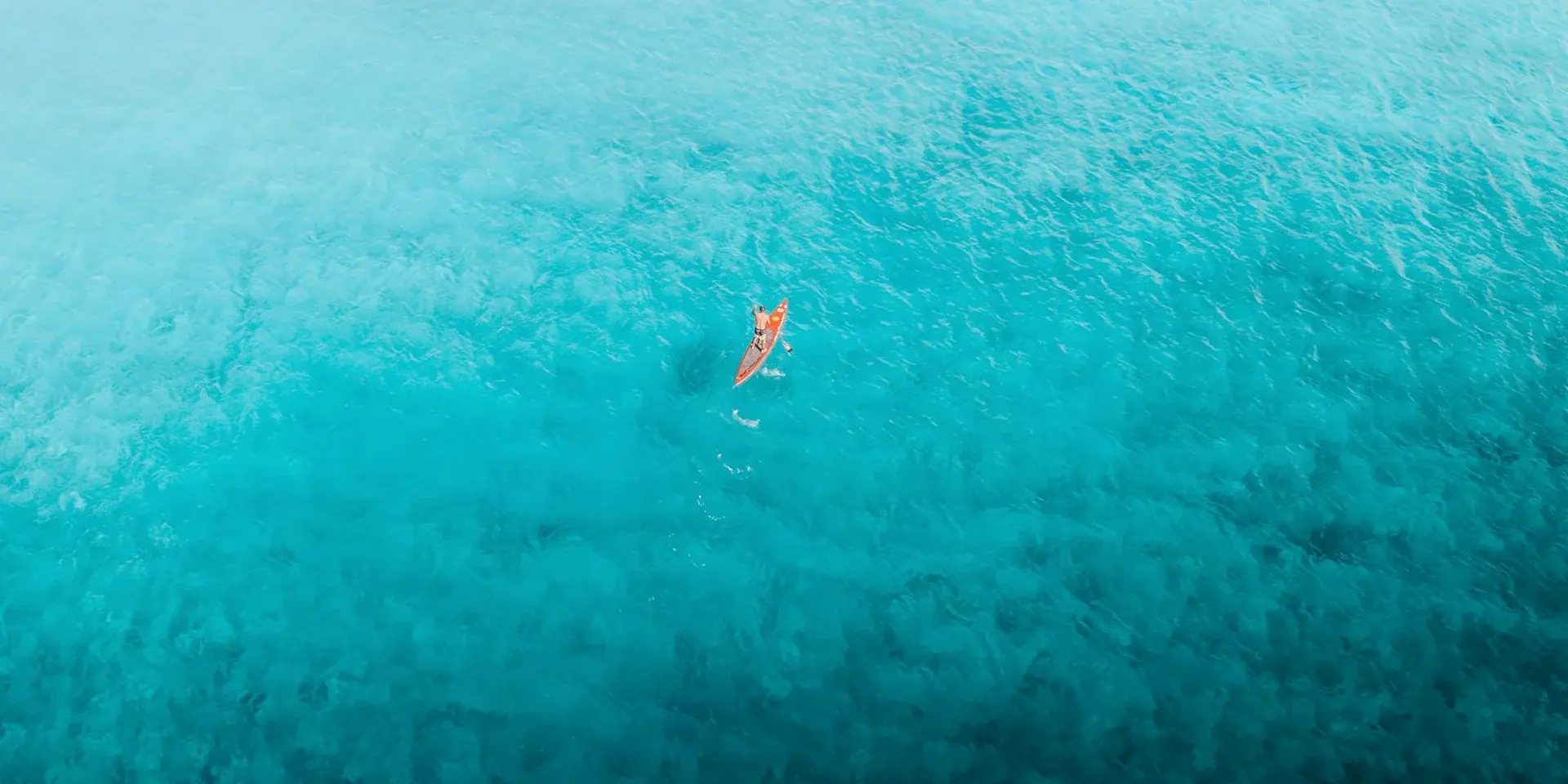 Paddleboarder crossing open turquoise water