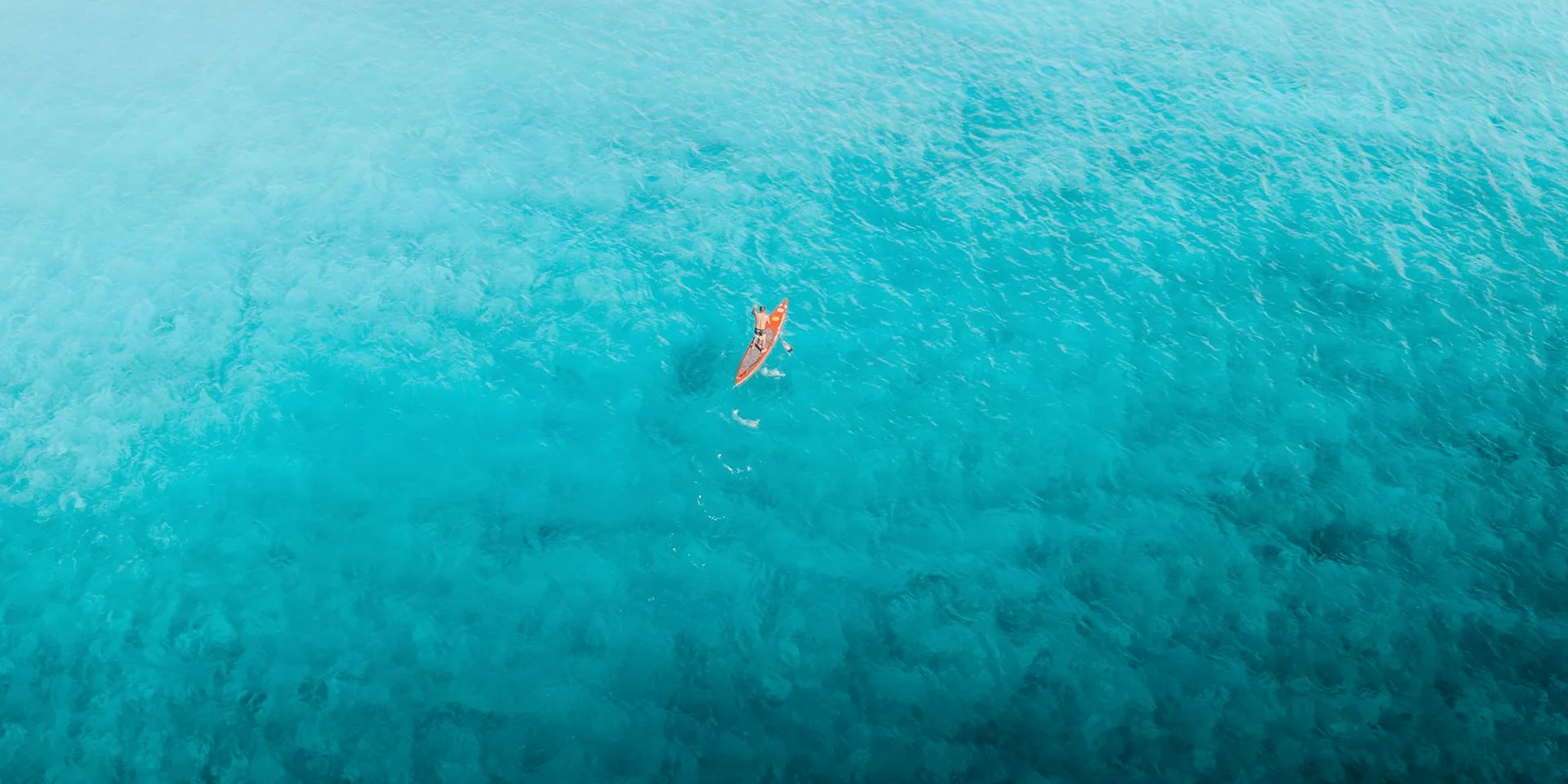 Paddleboarder crossing open turquoise water