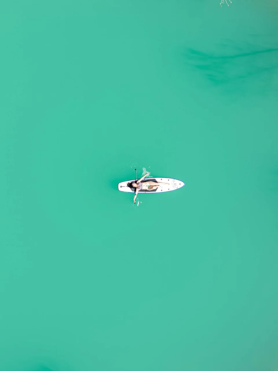 Paddleboarder enjoying a calm turquoise lake
